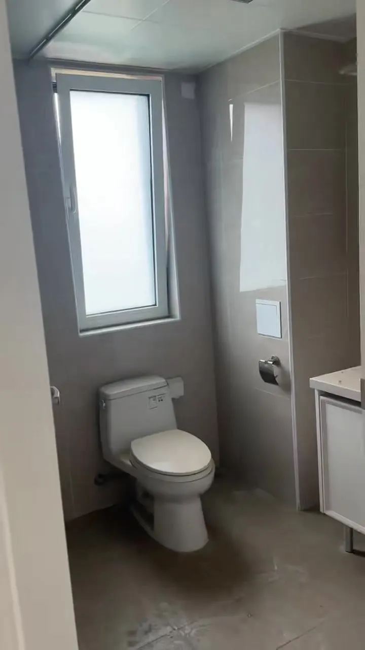 Real phone photo of the first flat's bathroom with a window and toilet
