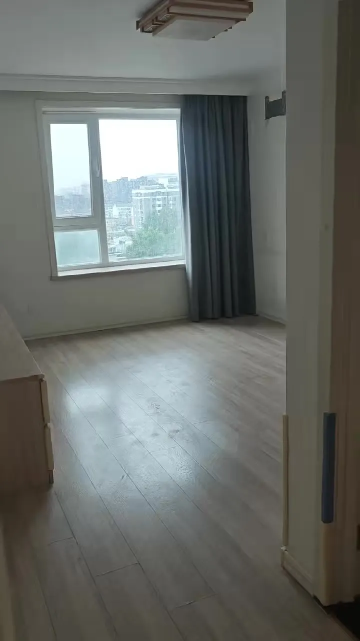 Real phone photo of the second flat's bedroom with a window and curtains
