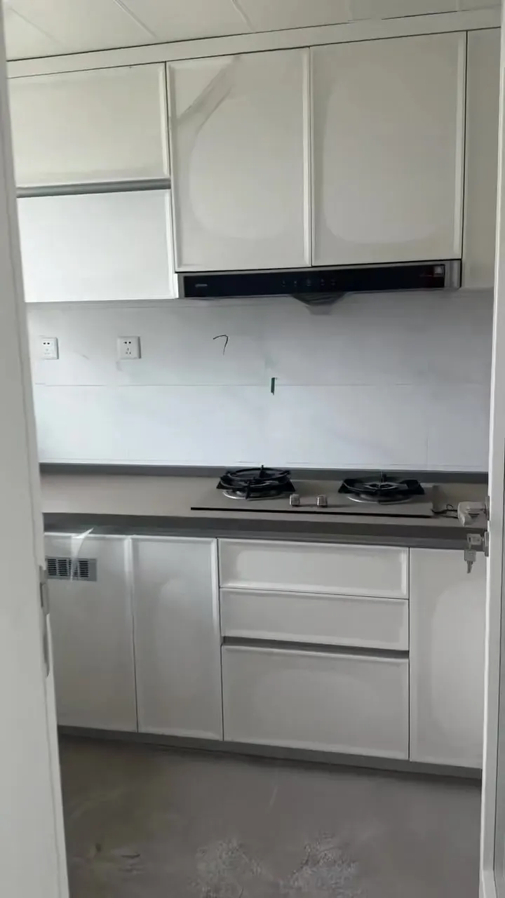 Real phone photo of a close-up of the first flat's kitchen wall and upper cabinets