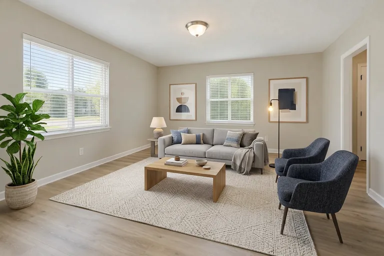 The same empty living room staged by this tool in a modern style, with a gray sofa, navy accent chairs and an oak coffee table